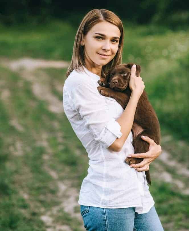 Photo of Young Girl Holding Brown Puppy In Arms Min